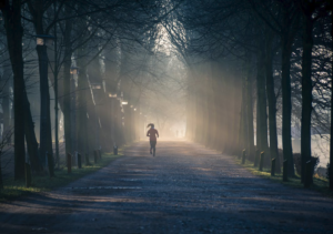 A person jogging on a trail with trees in the background.